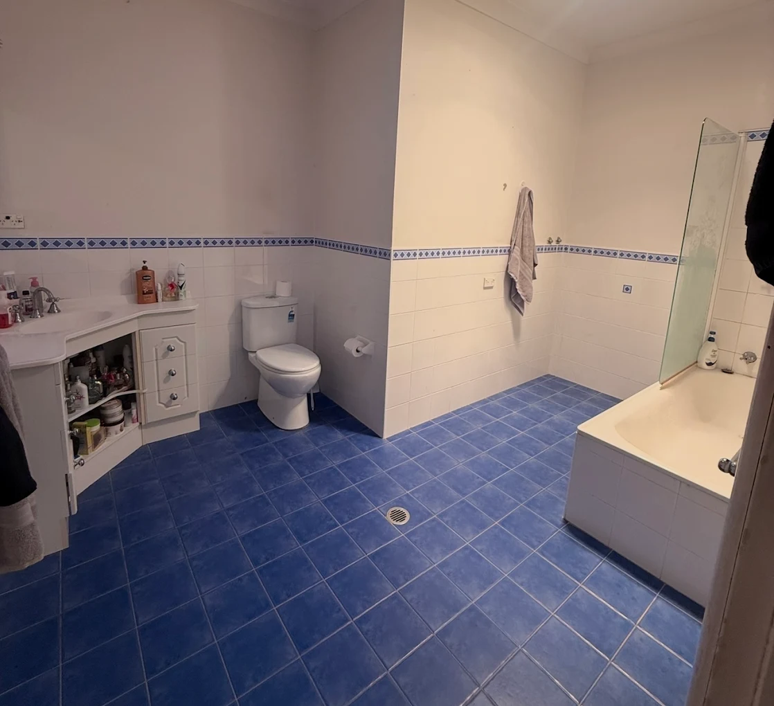 Dated bathroom with blue floor tiles before Quick Mick’s Plumbing renovated it in the Blue Mountains